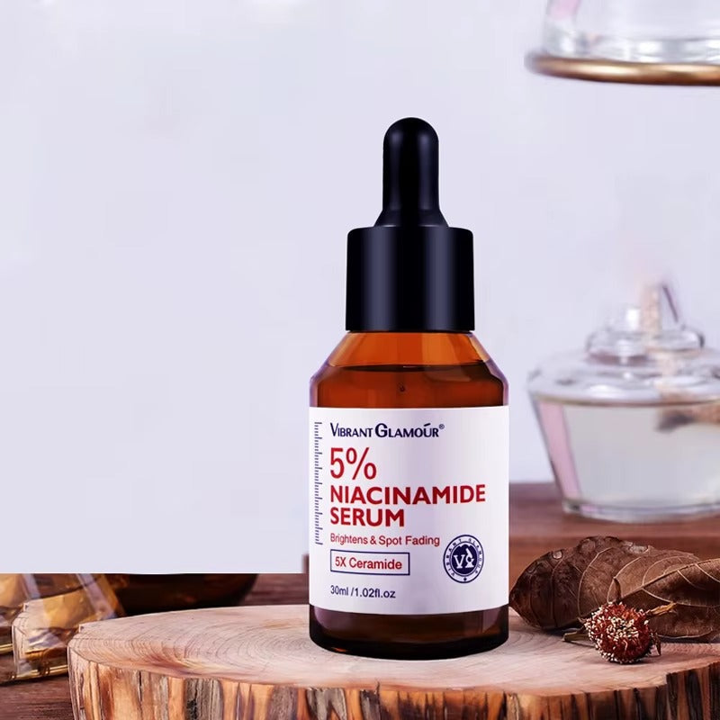A bottle of Vibrant Glamour 5% Niacinamide Serum with a dropper, placed on a wooden surface with a blurred background.