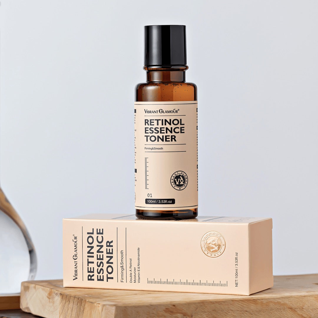 A bottle of Vibrant Glamour Retinol Essence Toner placed on its packaging box, with a white label and brown bottle.